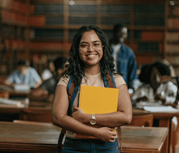 Student in the library smiling and preparaing for the Linguaskill exam