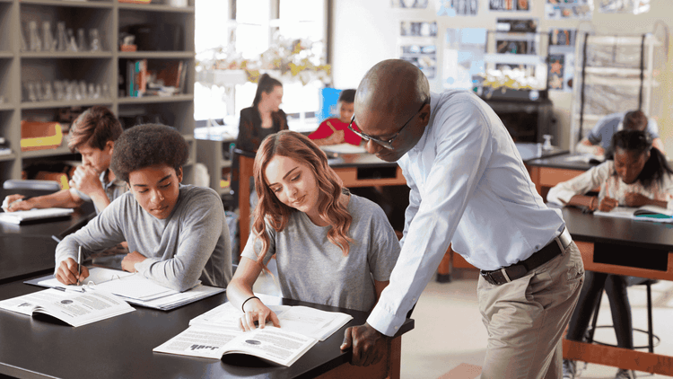 teacher with students in the classroom, checking the books with them