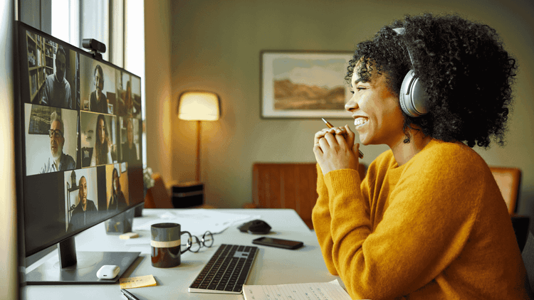 Young student with a yellow sweater in front of computer smiling